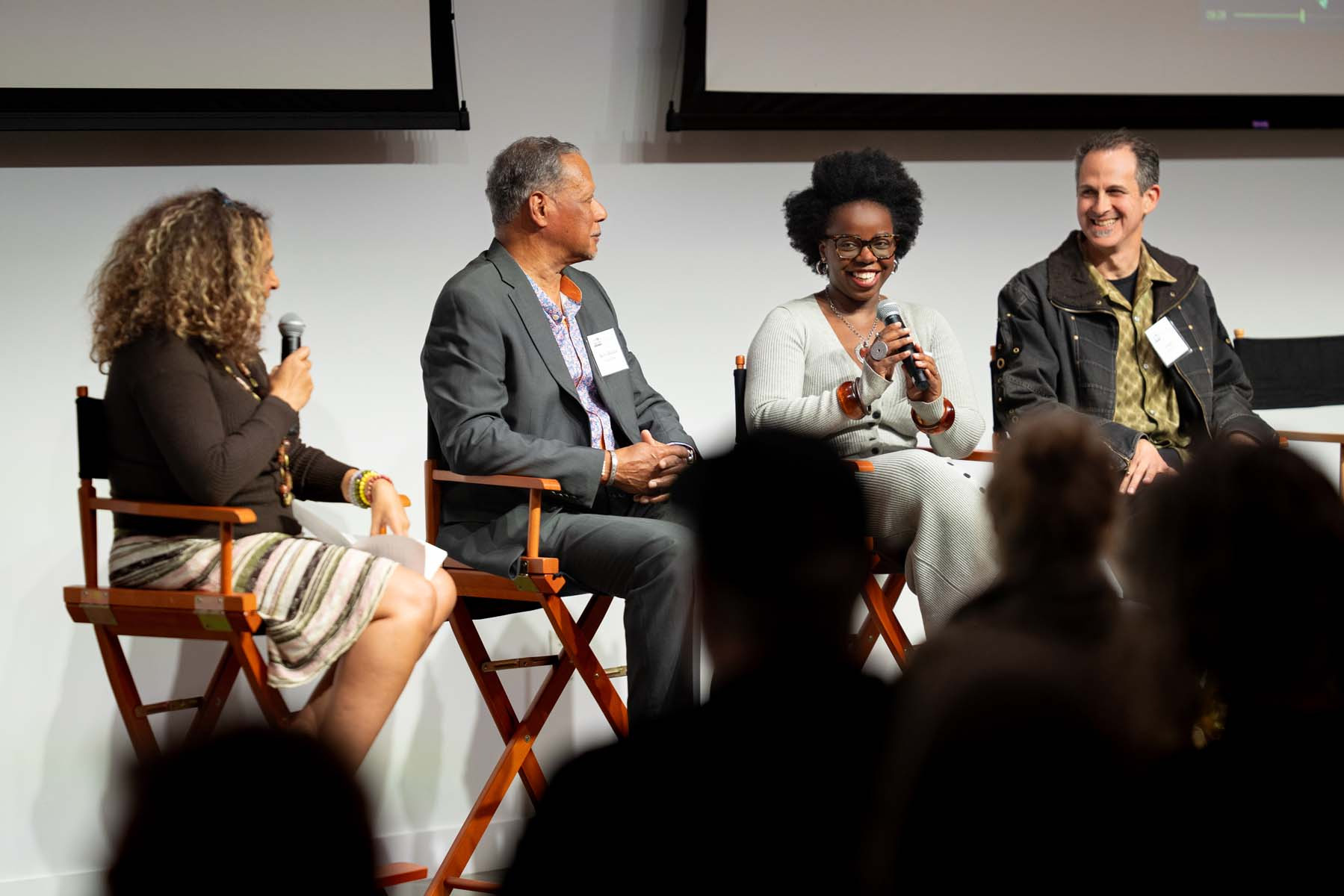 Four people sitting in director chairs engage in conversation.